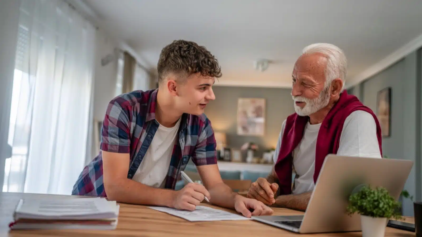 Teen helping old man with laptop