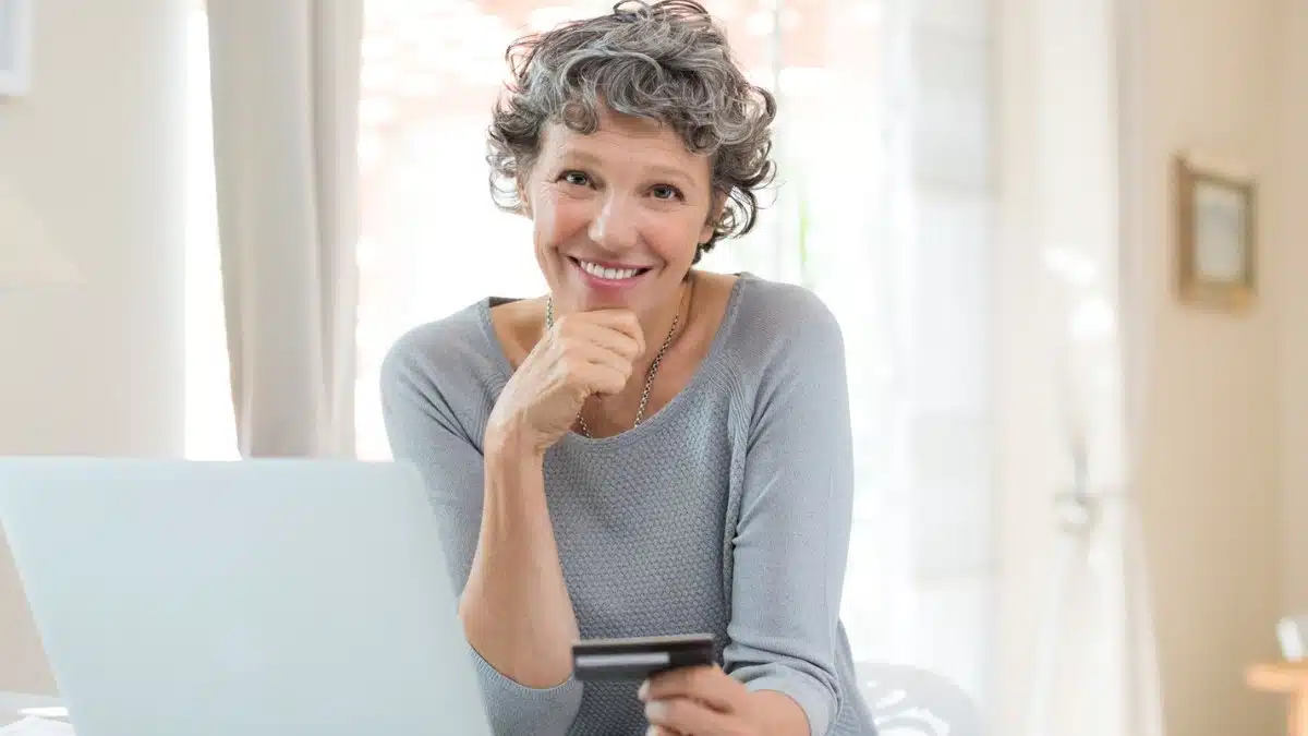 senior woman with laptop holding credit card