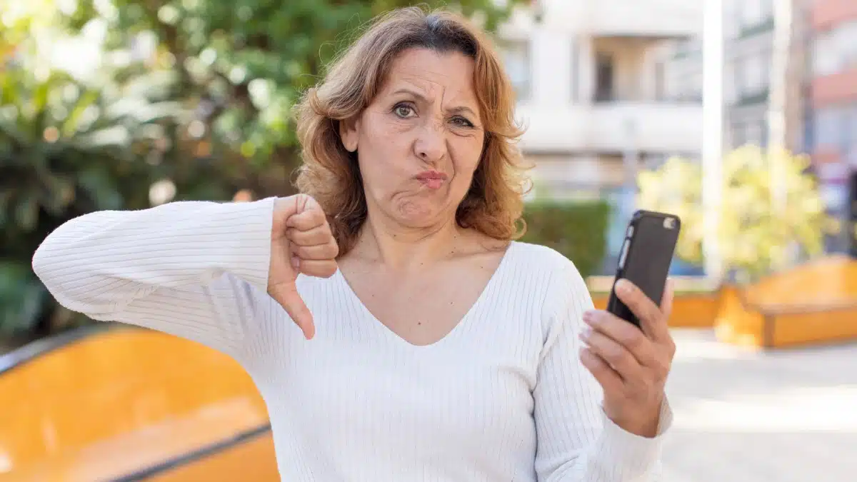 woman holding phone showig thmbsdown